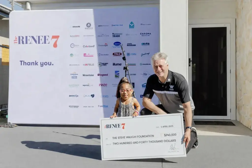 A smiling girl and a man kneel outside, holding a large donation check for $240,000 to The Steve Waugh Foundation. Behind them is a sponsor banner with logos and "Thank you" written on it.